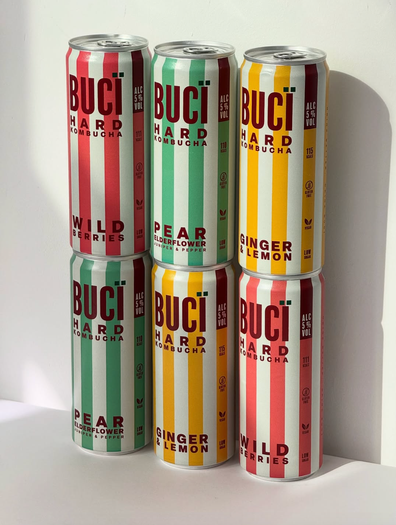 Six cans of different flavours of BUCI hard kombucha on a white background.