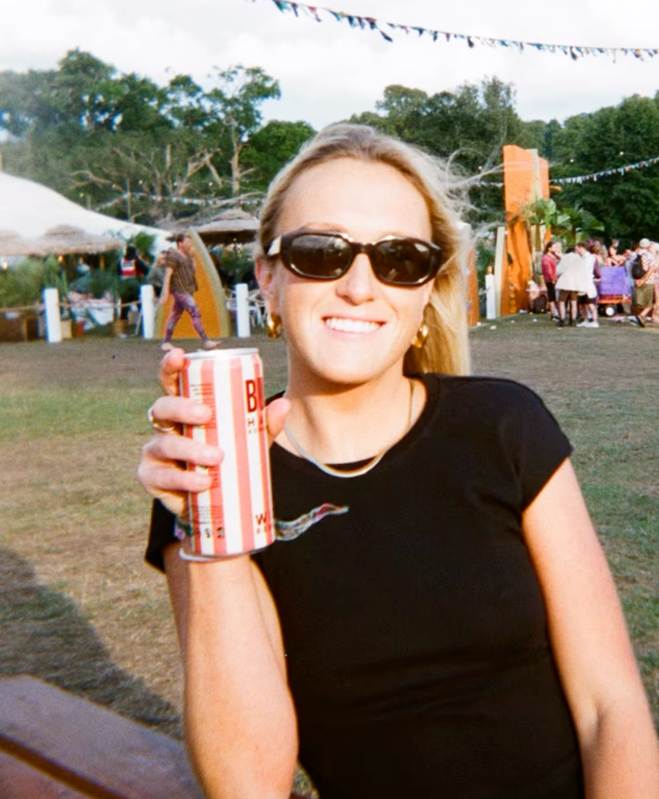 A person holding a can of BUCI wild berries hard kombucha in an outdoor setting